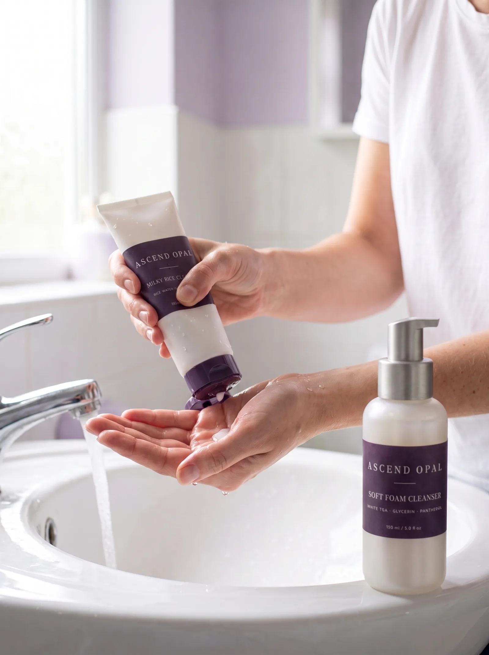Milky Rice Cleanser squeezed into a wet palm at a basin, with Soft Foam Cleanser on the edge